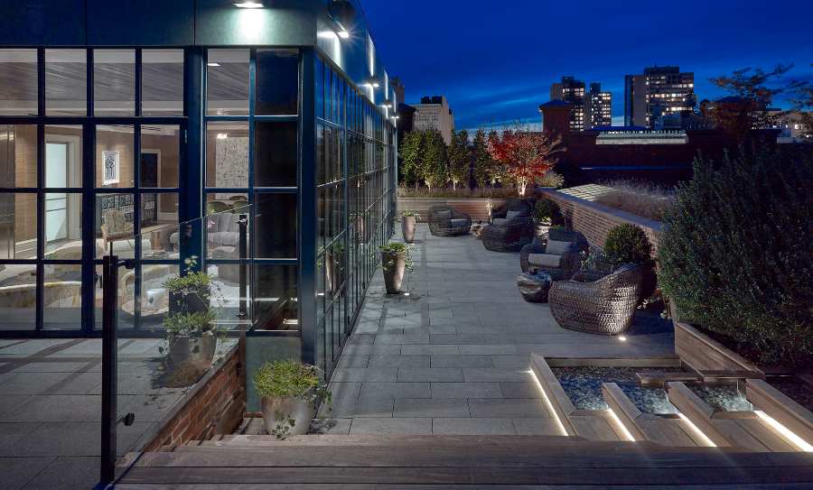 Fox-Nahem Associates, an open terrace in New York City with wood armchairs at night
