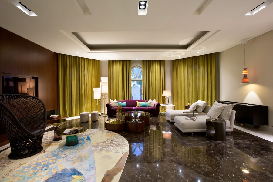 A colorful living room with black marble floor, several bespoke upholstery, a custom rug and a bespoke center table.