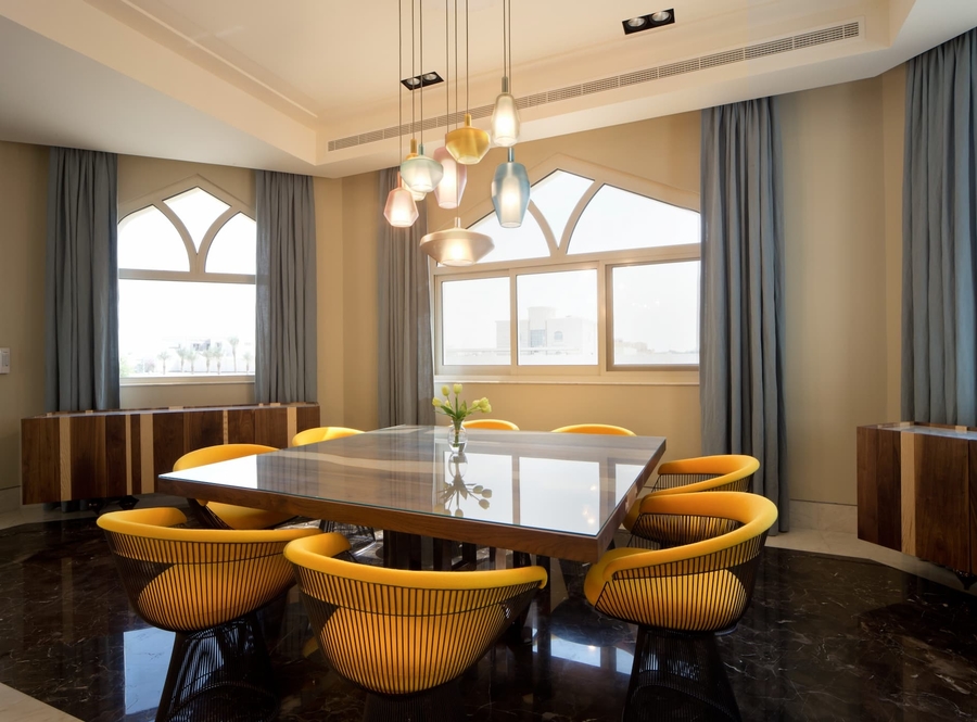A colourful dining room with yellow details accompanied with some bespoke upholstery and a wood dining table.