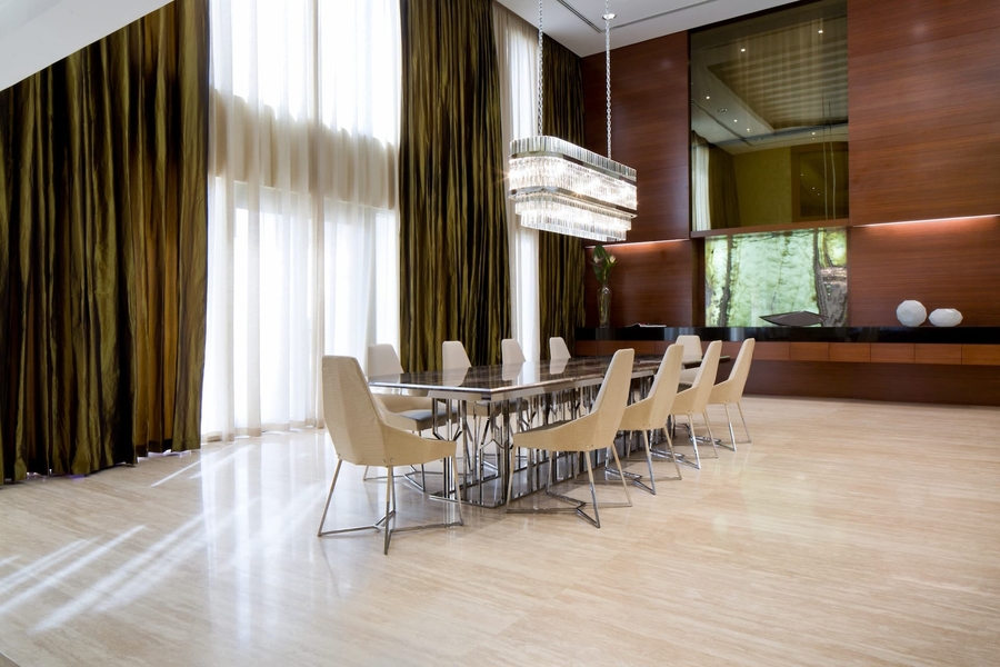 A dining room with custom made dining chairs, a bespoke table and a chandelier, in room with wood details.