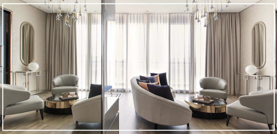 A living room with a mirror wall, furnished with a round sofa and a couple of armchairs.