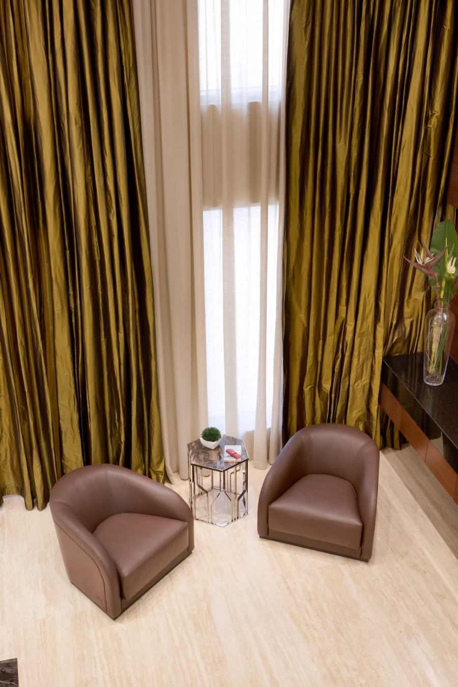 A living room with green and wood details accompanied by some bespoke upholstery and side table.