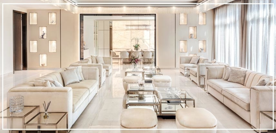 A living room with white marble floor several white upholstery with silver details.