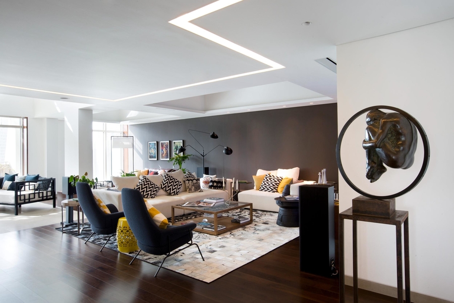 A living room with a lot of colour, with a rug, a couple of bespoke sofas and some custom armchairs.