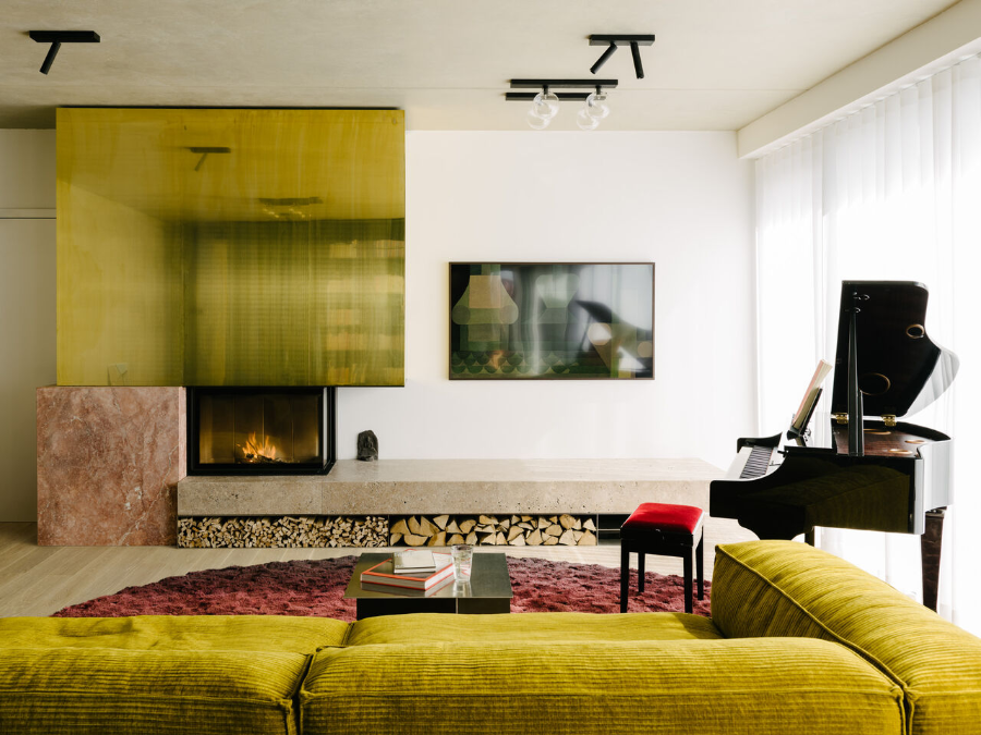 The Green Box project by ester bruzkus with a piano, a fireplace and a green sofa with a wine red carpet.