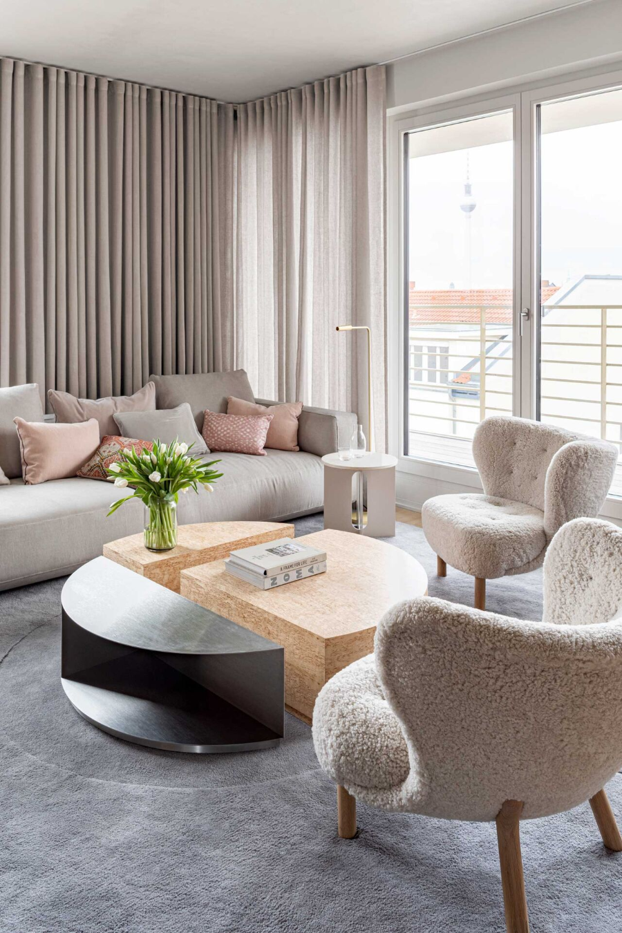 interior design idea with a grey/white dofa, a round white center table, 2 fluffly chairs and a round center table.