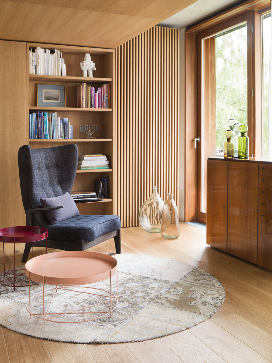 Esters Apartment reading corner with a purple armchair, a little pillow on top, two round side table, wooden floors, and a rug.