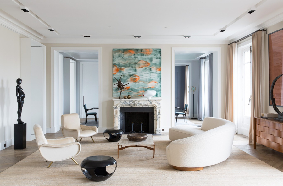 Damien Langlois-Meurinne presents Modern Interior Designs. Neutral living room with several artworks, round sofa, two armchairs, two black stools and a central table