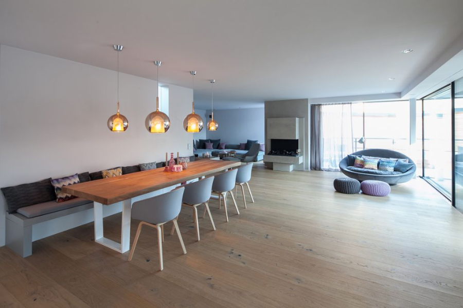 neubau Munich living room by BESPOKE with wood floors, 4 suspension lamps, a big dining table, and one round sofa.