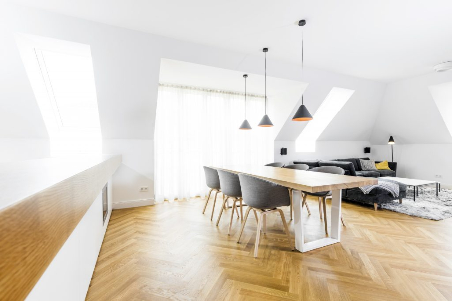 penthouse Maxvorstadt dining room by BESPOKE, with a wood dining table, suspension ligths, and the living room behind. 