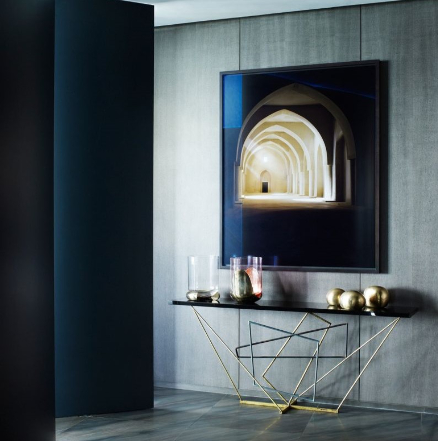 Interior Design Ideas with Yabu Pushelberg. This hallway has a console in black with golden details and a painting in dark blue colors that contrast with the grey walls. 