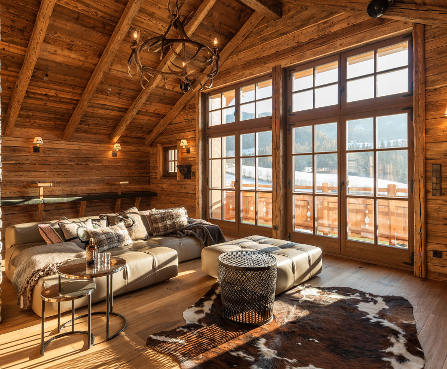 Frech Interior GmbH alpiner house with a sofa, some side tables and a chandelier.