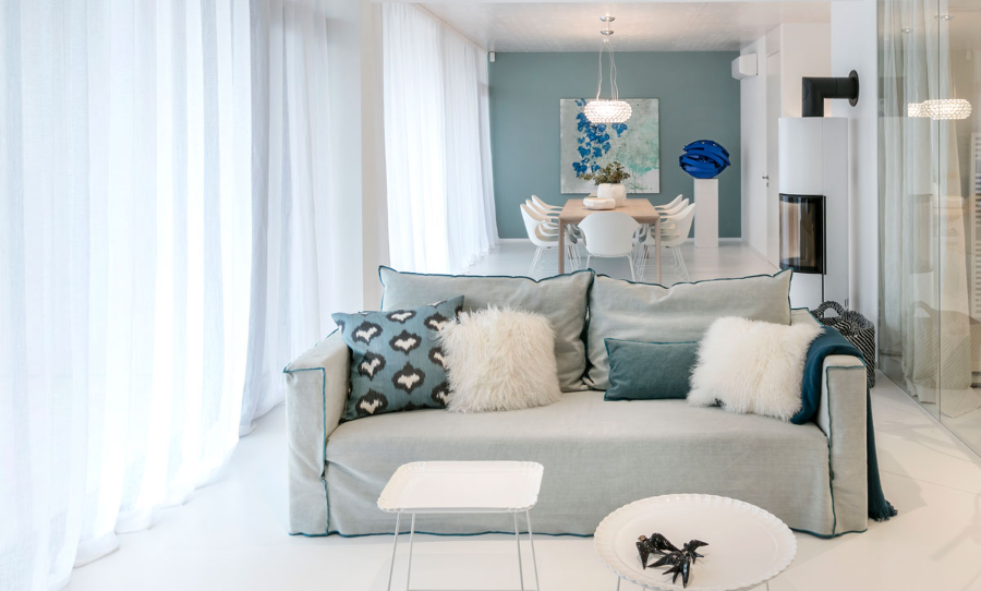 Frech Interior GmbH, haus am see living and dining space with a blue sofa, and a white pillow.