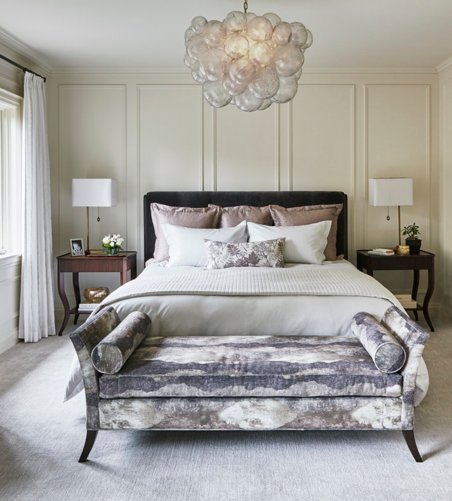 House decorating ideas by Laura Stein Interiors. This neutral bedroom has two side tables in wood, a dark bed frame, and a bench in blue and white.