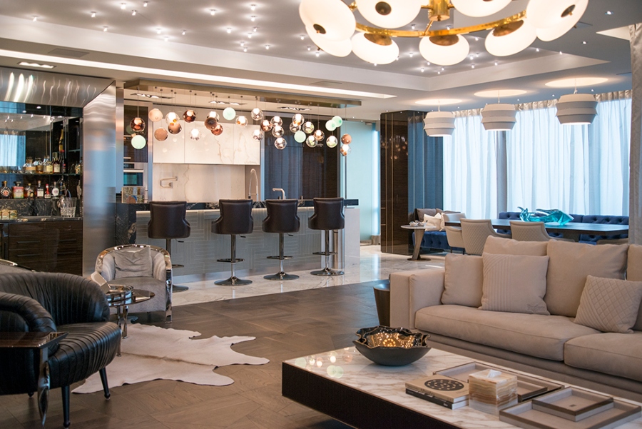 Modern Contemporary Interior Design by Fleur-de-lis Interior Design. This condo with an open space concept has a neutral sofa, a black armchair, a modern kitchen, and a dining room. 