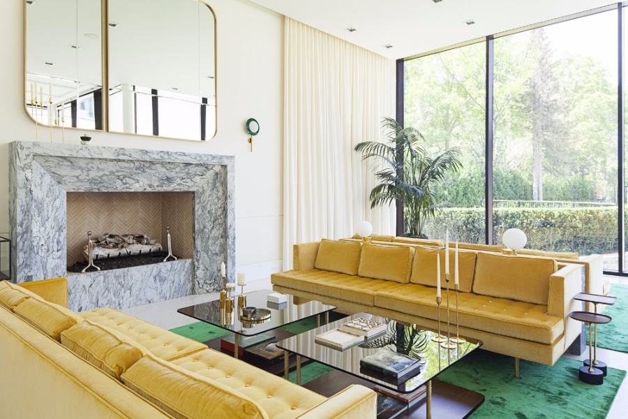 The Best Interior Design Ideas By Audax. This living room has two yellow sofas, a green rug, a fireplace in grey marble and above is a golden mirror. 