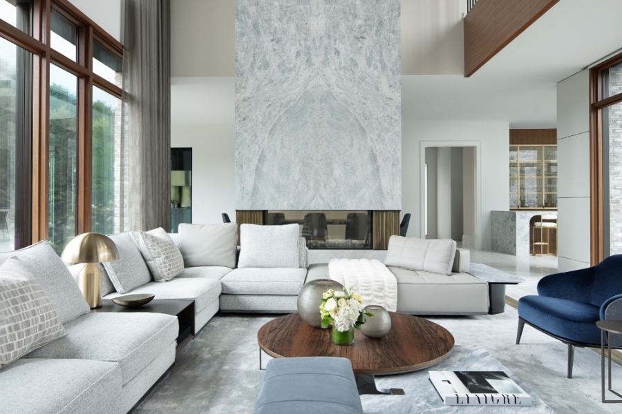 The Best Interior Design Ideas By Audax. This modern living room has a grey marble fireplace all way to the ceiling, a big modular sofa in grey, a blue armchair and a wood coffee table. 
