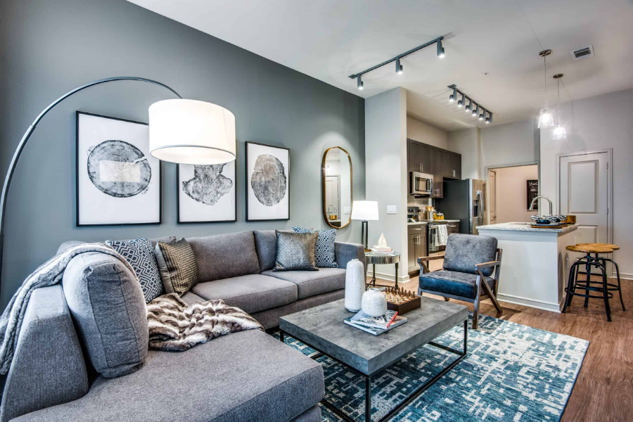 SJL Design Group: Interior Design In Texas. The main colors in this open space living room are blue and gray. There is a sofa, a center table and an armchair.