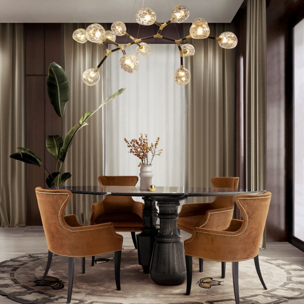 Welcome to a contemporary dining room designed in calming earth tones, where every detail enhances warmth and sophistication. The DUKONO Dining Chairs combine comfort and style, perfectly arranged around the striking PIETRA Oval Nero Marquina Dining Table by Boca do Lobo. Above, the HORUS Irregular Big Suspension Light casts a golden glow, while the CYRUS Table Light adds an additional layer of soft illumination. The HUANG Sideboard offers both storage and elegance, complemented by the CAY Rectangle Mirror, which amplifies light and depth in the space. On the floor, the METAMORPHOSIS Rug by Rug'Society grounds the room with texture and visual interest. Together, these pieces create a refined and inviting atmosphere, ideal for memorable dining moments.
